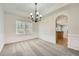 Elegant dining room with wainscoting, decorative lighting, and an arched entryway to the kitchen area at 4157 Medlock Woods Dr, Snellville, GA 30039
