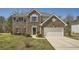 Charming two-story brick home with attached two-car garage, lush lawn and manicured shrubs at 4157 Medlock Woods Dr, Snellville, GA 30039