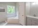 Elegant bathroom with a soaking tub, marble tiling, and a vanity with a white countertop at 4569 Campenille Trce, Suwanee, GA 30024