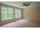 Bedroom with carpeted floors, two large windows overlooking a treed landscape and a ceiling fan at 4569 Campenille Trce, Suwanee, GA 30024