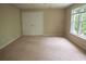 Spacious bedroom featuring neutral carpet, a double closet, and a bright window with natural light at 4569 Campenille Trce, Suwanee, GA 30024