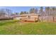 A backyard view of a tan house with a wooden deck and a lush green lawn at 1408 Lake Paradise Rd, Villa Rica, GA 30180
