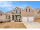 Inviting two-story brick home featuring a manicured lawn, two-car garage, and charming front porch at 2031 Broadmoor Way, Fairburn, GA 30213