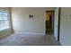 A carpeted bedroom with a large window and doorway, featuring neutral-colored walls at 545 Woodrow Dr, Lawrenceville, GA 30043