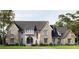 Stunning stone-and-shingle home featuring a arched entry, complemented by lush landscaping and a serene pathway at 133 Laurel Brook Ln, Canton, GA 30115