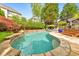Inviting backyard pool with stone waterfall features, lush landscaping, and comfortable lounge seating area at 1250 Rosette Way, Marietta, GA 30062