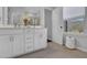 Bright bathroom featuring double sinks, large mirror, white cabinets, and a window at 235 Commons Ave, Woodstock, GA 30188