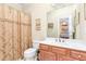 Well-lit bathroom with a vanity, toilet, and shower featuring a decorative curtain at 8095 Georgetown Cir, Suwanee, GA 30024