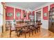 Formal dining room featuring vibrant red walls, elegant chandelier, and classic wood furniture on hardwood floors at 8095 Georgetown Cir, Suwanee, GA 30024