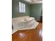 A relaxing soaking tub sits in this bathroom with decorative window and beautiful wood flooring at 3290 Spain Rd, Snellville, GA 30039