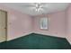 Cozy bedroom with a ceiling fan, green carpet, pink walls, and natural light from the window at 3290 Spain Rd, Snellville, GA 30039