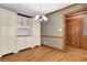 Dining area with hardwood floors, built-in cabinets with glass doors, and modern lighting fixture at 3290 Spain Rd, Snellville, GA 30039