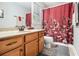 Bathroom featuring wood vanity, neutral countertop, and red patterned shower curtain, creating a stylish space at 4352 Treeline Way, Douglasville, GA 30135