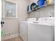 Functional laundry room with a side-by-side washer and dryer, plus a wire shelf and a window at 4352 Treeline Way, Douglasville, GA 30135
