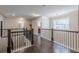 Upstairs hallway with hardwood floors and a wooden railing, leading to a bright bedroom at 614 Denali Dr, Mableton, GA 30126