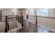 Upstairs hallway with hardwood floors and a wooden railing, leading to a bright bedroom at 614 Denali Dr, Mableton, GA 30126