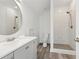 Modern bathroom featuring a round mirror, a white sink, gray vanity, toilet and walk-in shower at 7530 Heard Rd, Cumming, GA 30041