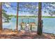 Dock featuring a sun deck, wooden chairs, and boat storage on a tranquil lake and wooded shoreline at 7530 Heard Rd, Cumming, GA 30041