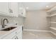 Well-lit laundry room with sleek cabinets, a stainless steel sink, and ample counter space at 7530 Heard Rd, Cumming, GA 30041