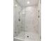 Modern shower with glass door, marble-style tile, and built-in shelves at 7530 Heard Rd, Cumming, GA 30041