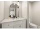 Elegant bathroom featuring a white vanity with marble countertop and a round-top mirror at 6170 Wellington Ct, Cumming, GA 30040