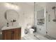 Bright bathroom featuring a wood vanity, circular mirror, and walk-in shower with glass door at 6170 Wellington Ct, Cumming, GA 30040