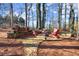 Outdoor fire pit area with stone base, stacked wood, and Adirondack chairs offers a cozy gathering spot at 6170 Wellington Ct, Cumming, GA 30040