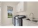 Bright laundry room with modern washer and dryer units, a sink, and ample storage space at 6170 Wellington Ct, Cumming, GA 30040