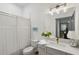 Bright bathroom with large mirror, elegant lighting, white vanity, and shower with curtain at 1171 Eggleston Sw St, Atlanta, GA 30310