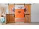 Garage with custom-built barn doors featuring sports team logo, partially open to a room with orange accent wall at 5669 Casa Blanca Ln, Atlanta, GA 30331