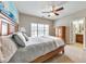 A sunny bedroom with a big bed, a ceiling fan, and view of the en-suite bathroom with double sinks at 2953 Kings Walk Ave, Marietta, GA 30062