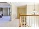 A naturally lit hallway with a wooden banister leads to a carpeted bedroom and a stunning chandelier at 2953 Kings Walk Ave, Marietta, GA 30062