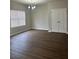 Living area with wood-look flooring, double closet, bright window and modern chandelier at 4373 Trake Way, Ellenwood, GA 30294