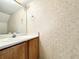 Bathroom showcasing a pedestal sink, a mirror, and patterned wallpaper at 5916 Dogwood Mnr, Lithonia, GA 30038