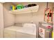 Functional laundry area featuring a washing machine, dryer, water heater, and storage shelf at 115 Hollybrook Rd, Atlanta, GA 30349