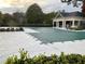 View of the community pool with a cover surrounded by a clubhouse and greenery at 5027 Bayrose Cir # 27A, Atlanta, GA 30344