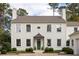 Elegant two-story white home with a dark front door, brick driveway, and beautiful landscaping at 2629 Ashford Ne Rd, Brookhaven, GA 30319