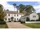 Elegant white home featuring a brick driveway, green lawn, and attached three-car garage at 2629 Ashford Ne Rd, Brookhaven, GA 30319