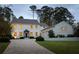 Elegant two-story white home at dusk featuring a brick driveway, attached garage, and manicured landscaping at 2629 Ashford Ne Rd, Brookhaven, GA 30319