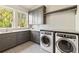 Bright laundry room with gray cabinets, folding counter, and modern washer and dryer with large windows at 2629 Ashford Ne Rd, Brookhaven, GA 30319