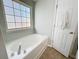 Bathroom features a window above a soaking tub, a white door, and neutral walls and floors at 530 Firethorn Ct, Villa Rica, GA 30180