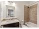 Well-lit bathroom featuring shower over tub, granite countertops, and a decorative mosaic accent wall at 2111 Lilly Nw Way, Atlanta, GA 30318