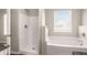 Bright bathroom featuring a shower, soaking tub, and window for natural light at 325 Nutwood Trce, Locust Grove, GA 30248