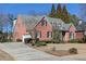 Charming red brick home featuring a lush lawn, manicured bushes, grey roof, and an attached garage at 3894 Stone Lake Nw Dr, Kennesaw, GA 30152