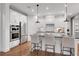 Modern white kitchen with stainless steel appliances, center island with bar stools, and hardwood floors at 6095 Marigold Way, Atlanta, GA 30349