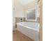 Bathroom with a soaking tub, tile surround, and large window at 250 High Court Way, Locust Grove, GA 30248