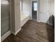 Main bathroom featuring a walk-in shower, soaking tub, and dark wood-look flooring at 215 Bradley St, Covington, GA 30016