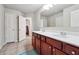 Bathroom with a double sink vanity, white countertops, dark cabinets, and access to an open closet at 615 Ceremony Way, Acworth, GA 30102