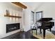 Close-up of a modern fireplace with a mantle, tiled surround, grand piano, and hardwood floors at 320 Spyglass Blf, Alpharetta, GA 30022