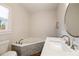 Bright bathroom featuring a corner bathtub with decorative stone accents, window, and quartz vanity at 915 Homer Rd, Woodstock, GA 30188